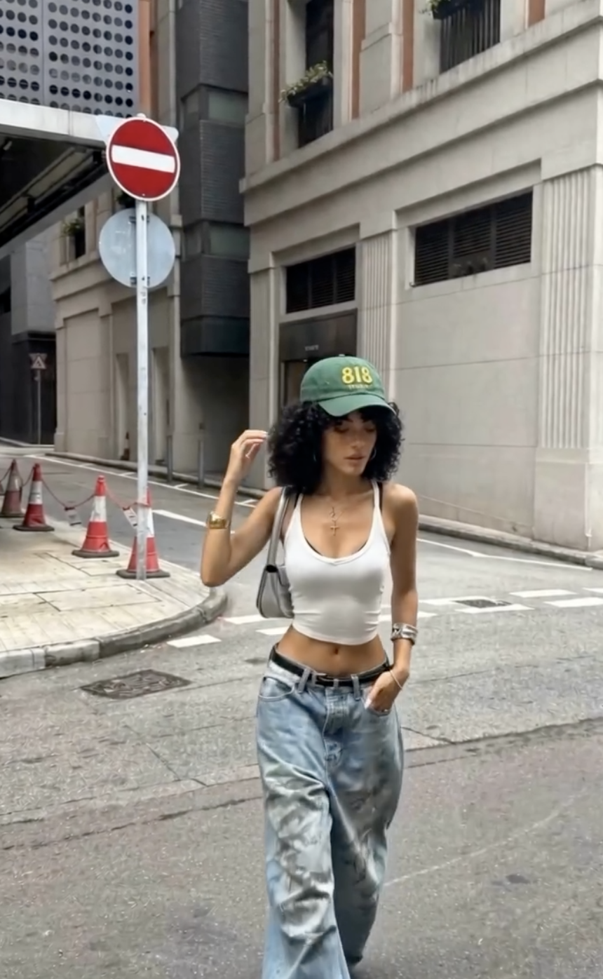 Layla Rey crossing a Hong Kong side street in a white tank and baggy denim